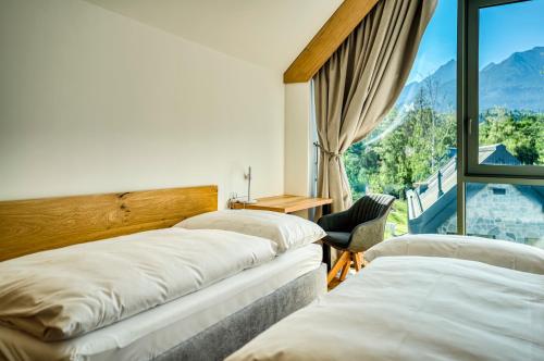 two beds in a room with a large window at Apartmány a Chalety Horizont Resort in Stará Lesná