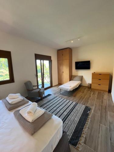 a bedroom with two beds and a chair and a television at Paralia Homes peaceful 2 bedroom, unit # 2 in Kriopigi