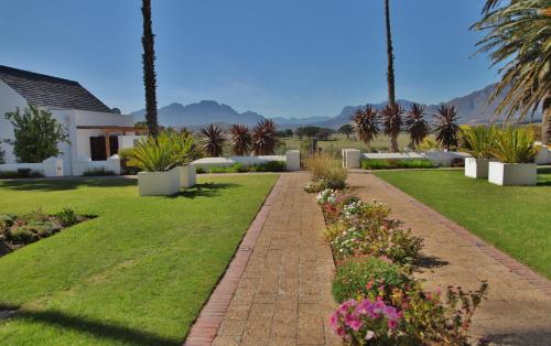 a garden with palm trees and a brick path at Wild Mushroom Country House in Stellenbosch
