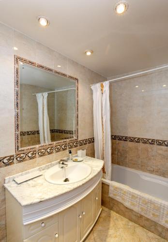un bagno con un lavandino, una vasca e uno specchio di Casa de Ana Rosa a Málaga