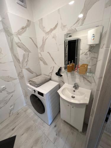 a white bathroom with a sink and a mirror at New York Apartments in Katowice