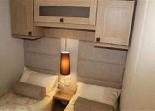 a bedroom with two beds and a lamp on a table at Roxbury 5 Star 6 berth Luxury Caravan in Exeter