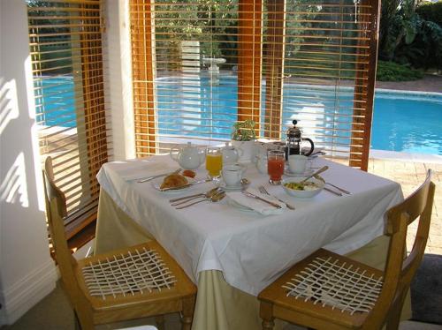 a table with a white table cloth and chairs and a table with food at Cotswold House in Cape Town