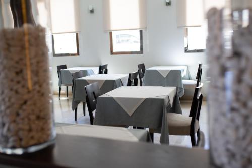 ein Esszimmer mit weißen Tischen, Stühlen und Fenstern in der Unterkunft Hotel El Trebol in Carboneras