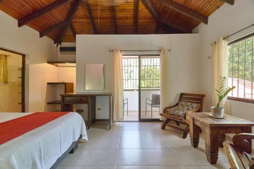 1 dormitorio con cama, escritorio y silla en Villa Bayacanes con piscinas privadas, en Jarabacoa