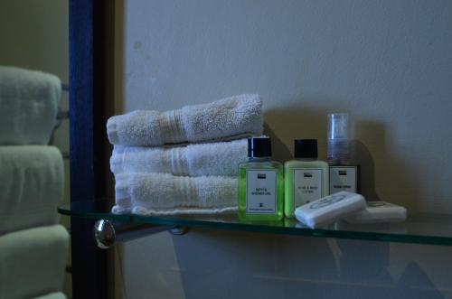 a glass shelf in a bathroom with towels and soap at D'Aria Guest Cottages in Durbanville