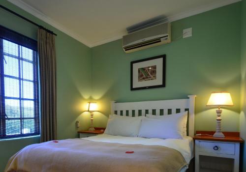 a bedroom with green walls and a bed with two lamps at D'Aria Guest Cottages in Durbanville