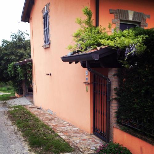 an orange building with a gate and plants on it at B&B Villa Rossana in Langhirano