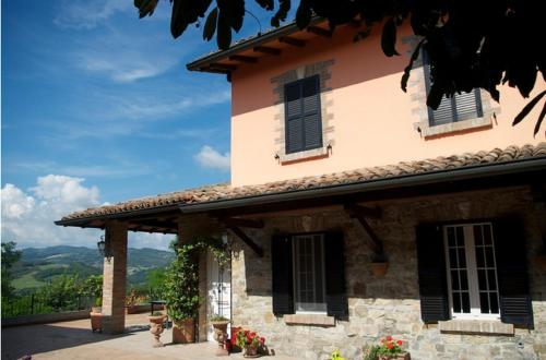 a stone house with black shutters and flowers at B&B Villa Rossana in Langhirano
