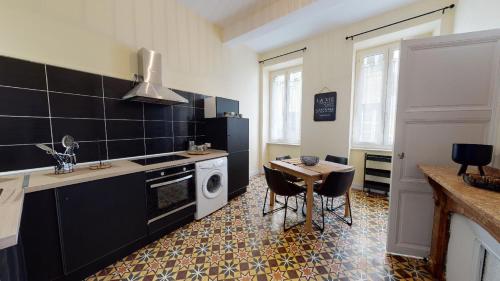 une cuisine avec des appareils en noir et blanc et une table dans l'établissement Le Casimir - Appartement de standing 90m2 - Carcassonne centre, à Carcassonne