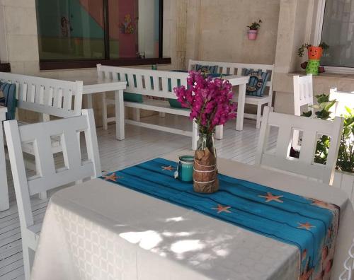 a table with a vase of flowers on a table with chairs at Familia Fantastiko - Family Hotel in Kiten