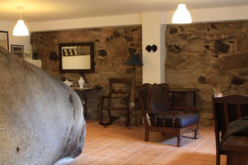 a room with a chair and a large rock wall at Casa do Arco - Casa de Campo in Mezio