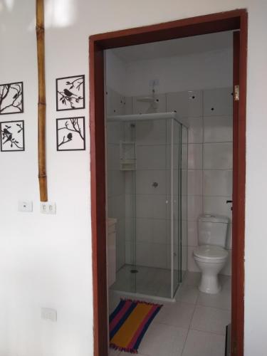 y baño con ducha de cristal y aseo. en La Casa Rozada Prumirim en Ubatuba