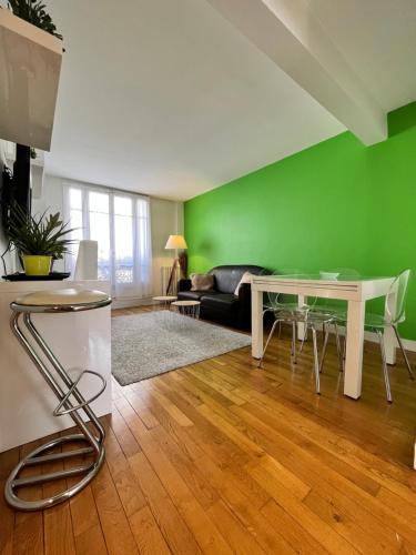 - un salon avec une table et un mur vert dans l'établissement Superbe Appartement 2P PARIS Boulogne Roland Garros, à Boulogne-Billancourt