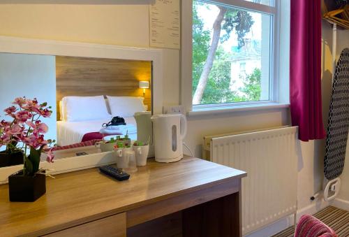 a bedroom with a bed and a desk with a mirror at Piccadilly Hotel in Bournemouth