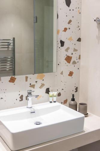 a bathroom with a white sink and a mirror at Ntinas Filoxenia Hotel & Spa in Skala Potamias