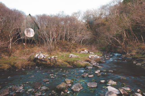 a river with rocks and trees in the background at Fernwood in Clifden