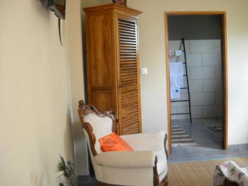 a room with a chair with an orange pillow on it at Bois de Santal in Saint-Pierre