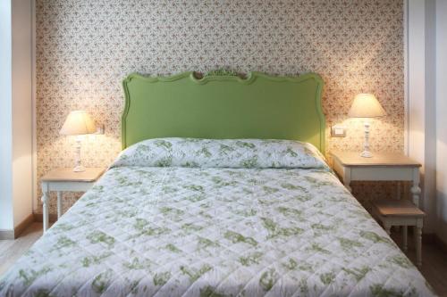a bed with a green headboard and two night stands at DormidaNoi B&B in Civitanova Marche