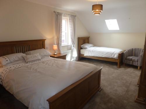a bedroom with two beds and a chair and a window at Oatlands Self Catering Lets in Hillsborough