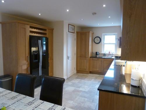 a kitchen with a black refrigerator and wooden cabinets at Oatlands Self Catering Lets in Hillsborough