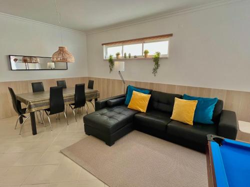 a living room with a black leather couch and a table at Arte de Marinheiro in Sesimbra