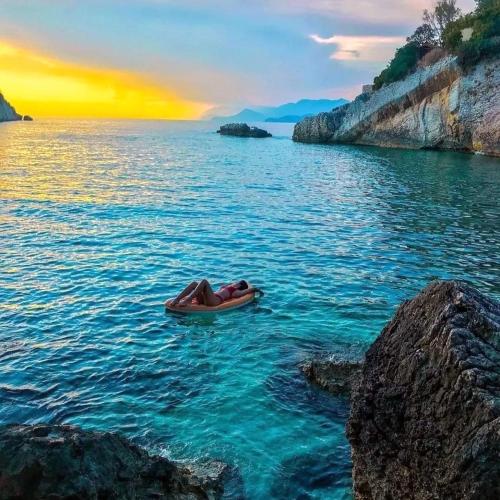 a person in a boat in the water at sunset at Apartments Dragišić in Sveti Stefan
