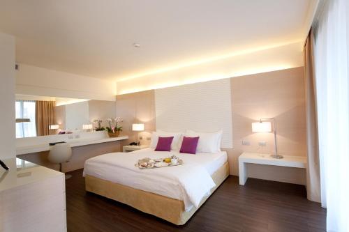 a bedroom with a large white bed with purple pillows at Laguna Palace Hotel Grado in Grado