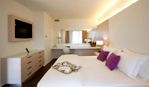 a bedroom with a white bed with a tray on it at Laguna Palace Hotel Grado in Grado