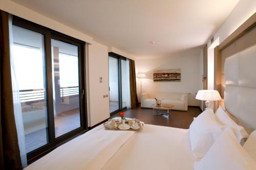 a bedroom with a white bed and a large window at Laguna Palace Hotel Grado in Grado