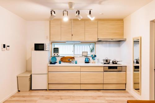 IsumiNagisa no Shiroi Ie Laguna / Vacation STAY 73153的厨房配有木制橱柜和白色冰箱。