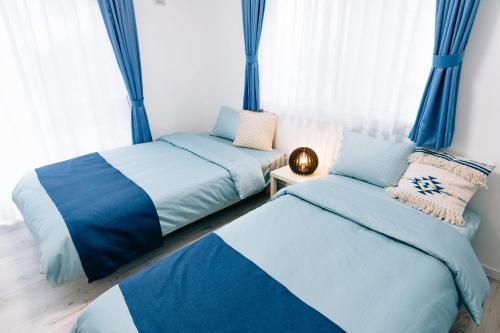 IsumiNagisa no Shiroi Ie Laguna / Vacation STAY 73153的一间卧室设有两张床,窗户配有窗帘