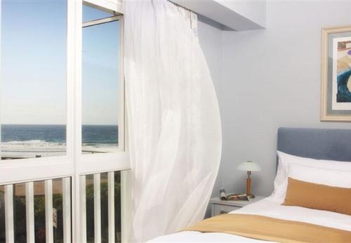 een slaapkamer met een raam met uitzicht op de oceaan bij The Calders Hotel & Conference Centre in Fish hoek