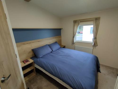 a bedroom with a blue bed and a window at Luxury 3 Bedroom Caravan Near Edinburgh in Port Seton