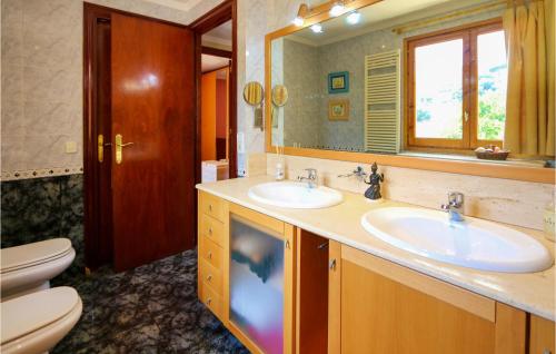 baño con 2 lavabos, espejo y aseo en 4 Bedroom Gorgeous Home In Sant Cebria De Vallalt, en Sant Cebrià de Vallalta