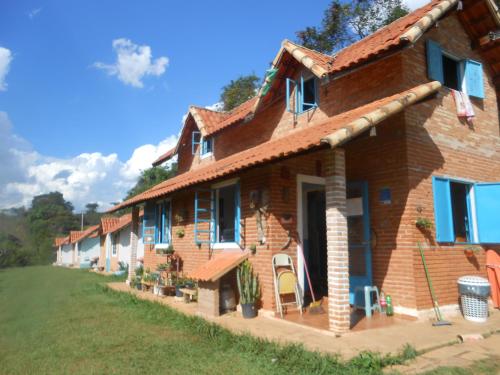 Casa de ladrillo con ventanas azules y patio en Pousada Shangrilá São Thomé, en São Thomé das Letras