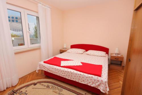 a bedroom with a red and white bed and a window at Apartments by the sea Postira, Brac - 5152 in Postira