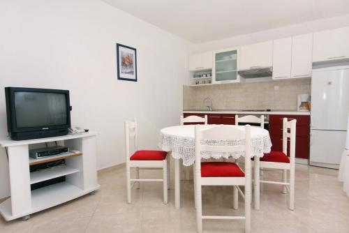 a kitchen with a table with chairs and a television at Apartments by the sea Postira, Brac - 5152 in Postira