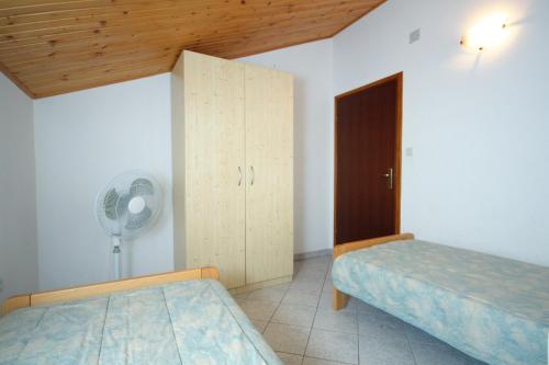 a bedroom with two beds and a closet and a fan at Apartment Grebastica 4867a in Grebaštica