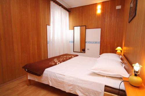 a bedroom with a white bed with wooden walls at Apartments by the sea Jezera, Murter - 5063 in Jezera