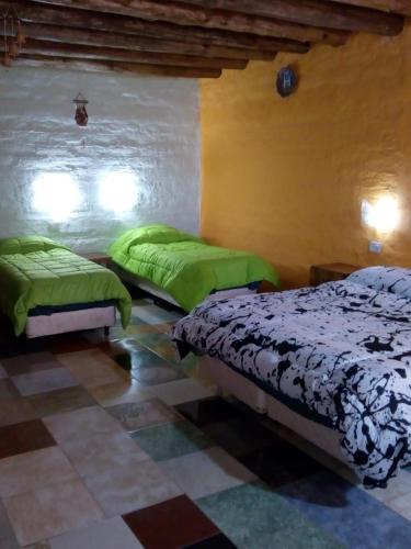 two beds in a room with green sheets at Hotel de Campo Oeste Paraíso in La Ciénaga