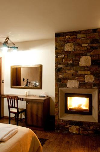a bedroom with a fireplace and a bed and a mirror at Belina Hotel in Portariá