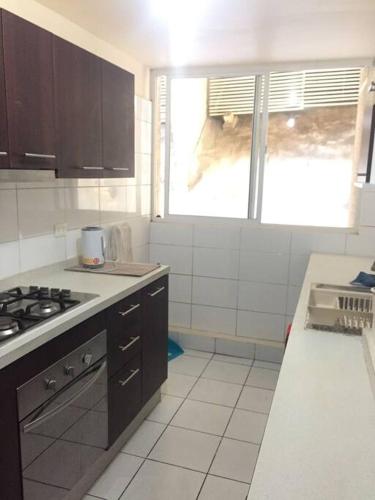 a kitchen with black cabinets and a stove top oven at Grande Departamento, Frente al Mar, Equipado. in Valparaíso