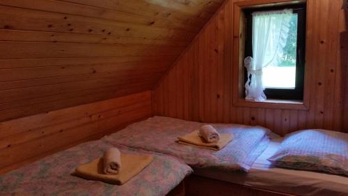 Dos camas en una cabaña de madera con sombreros. en Počitniška hiša Ukanc, en Bohinj