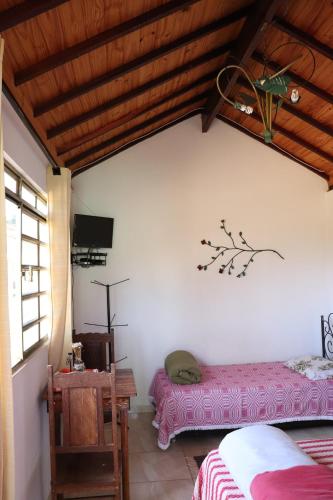 a bedroom with a bed and a table and a tv at Chalés Excalibur in São Thomé das Letras