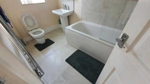 Spacious 3-bedroom home in Birmingham with driveway parking في برمنغهام: حمام مع مرحاض وحوض استحمام ومغسلة