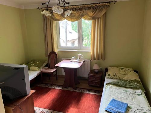 Habitación con 2 camas, mesa y ventana en Bar Sandacz, en Inowłódz