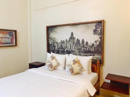 a bedroom with a white bed with a picture on the wall at My Key Polanka Pirvate Villa with Pool in Siem Reap