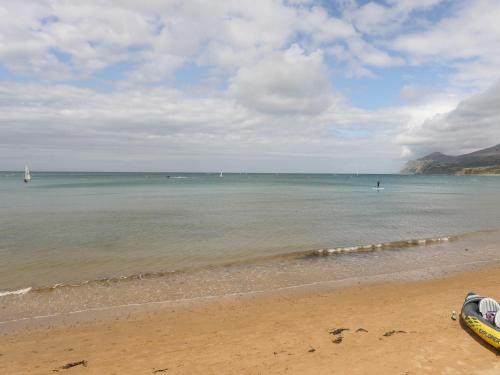 a view of the beach with a boat in the water at Bwthyn Bach in Nefyn
