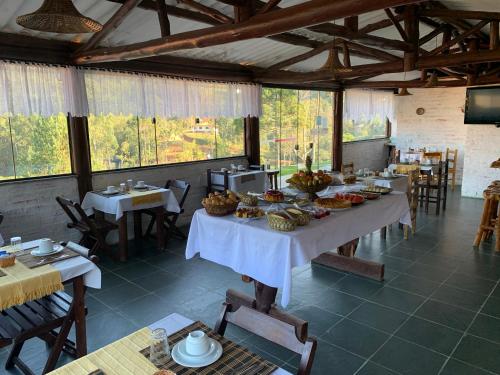 a dining room with tables with food on them at Chales Bela Serra in Monte Verde